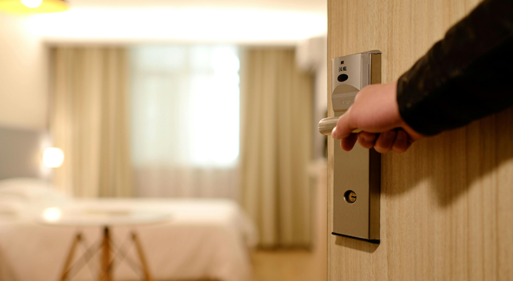 Traveler inspecting hotel room door lock as part of hotel safety tips