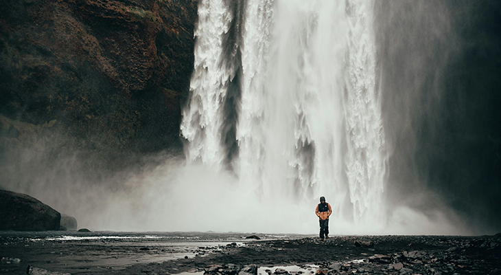 iceland solo female traveler standing by Skógafoss waterfall