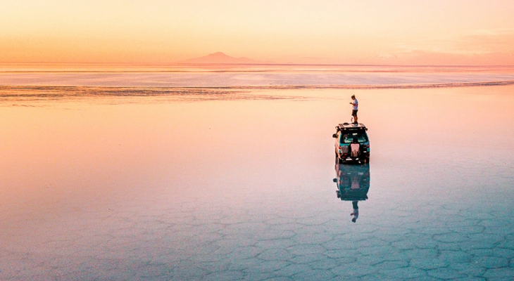 Traveler overlooking remote salt flats reflecting the sky