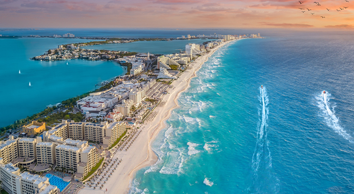 Warm places to visit in December: tropical beach at sunset with palm trees and soft waves